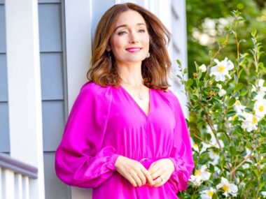 Antonia leaning on a post on her porch wearing Fluro pink