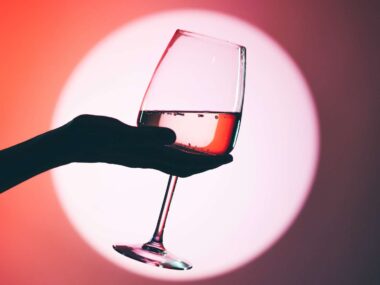 A hand holding a wine glass in a spotlight