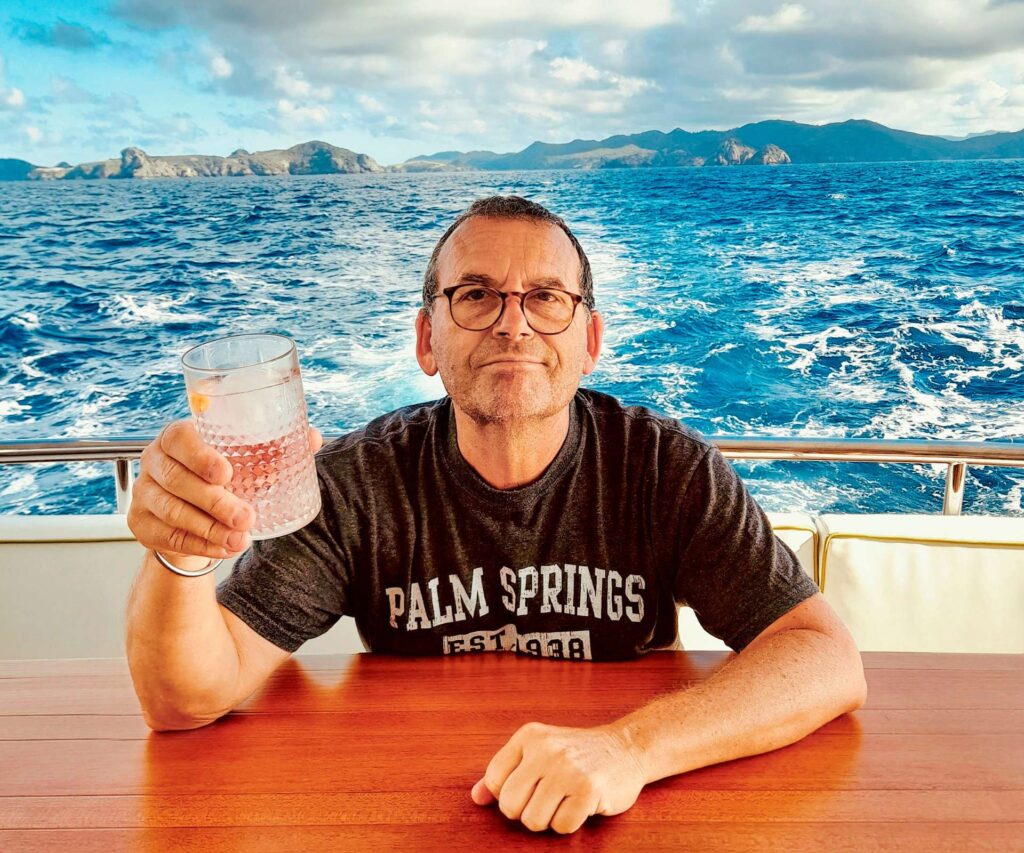 Paul holding up a glass of gin on the back of his boat