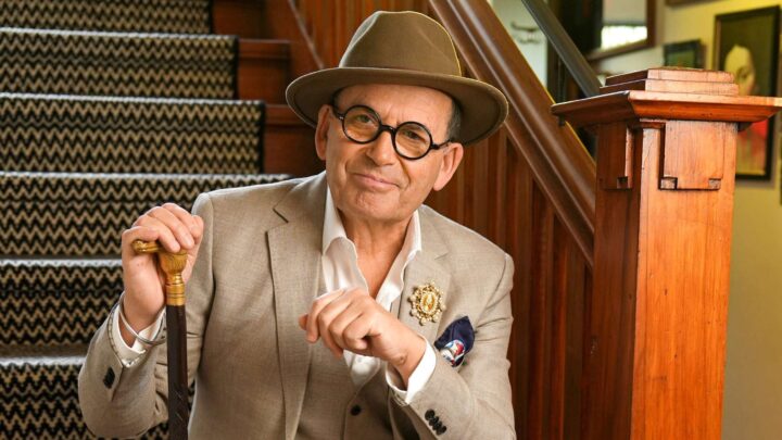 Paul Henry siting on some stairs with his cane in one hand and a bowler hat on his head