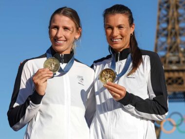 Brooke and Lucy holding up their 2024 Olympic medals in front of the Eiffel Tower