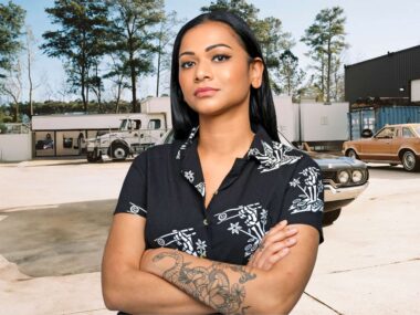 Shoshana Sachi standing with her arms crossed in a car yard