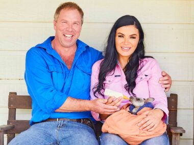 Claire and Andrew sitting on a bench while Claire feeds a baby kangaroo