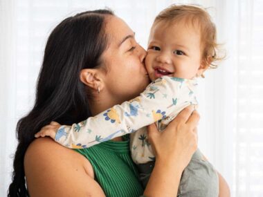 A Māori mother kissing her baby on the cheek